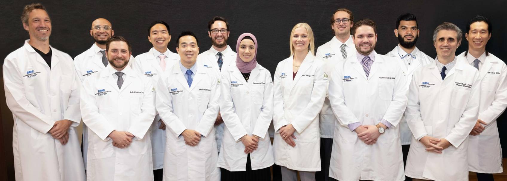 Residents in lab coats standing in group smiling 